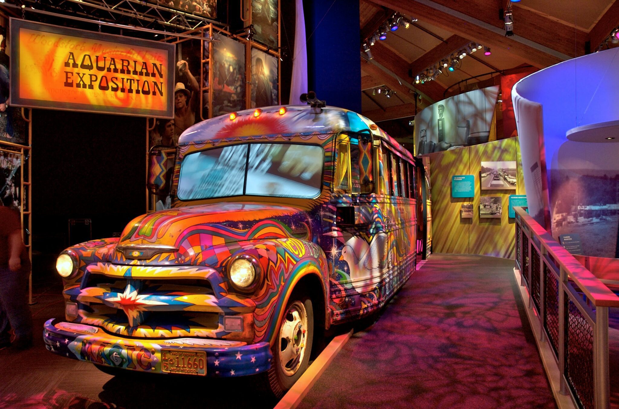 A school bus painted in bright psychedelic colors and designs sites in a museum as part of an exhibit. 
